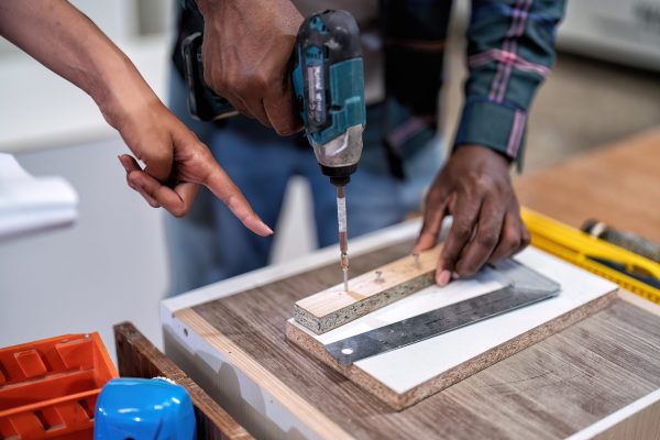 In wooden industrial senior carpenter teach trainee engineer use power tool drilling screw to wood